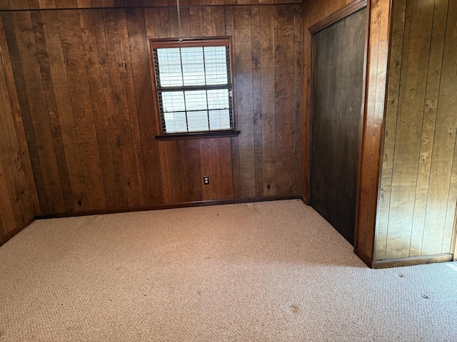 unfurnished room with light carpet and wooden walls