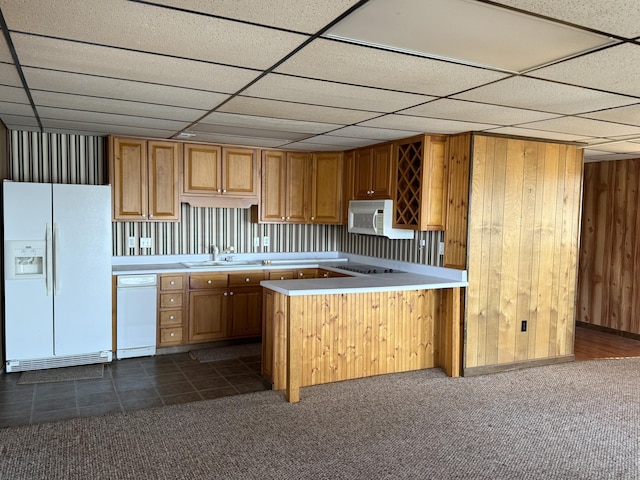 kitchen featuring a peninsula, white appliances, a sink, light countertops, and dark colored carpet