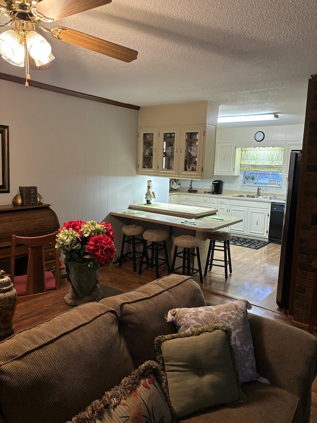 living area with light wood-style flooring, a textured ceiling, and ceiling fan
