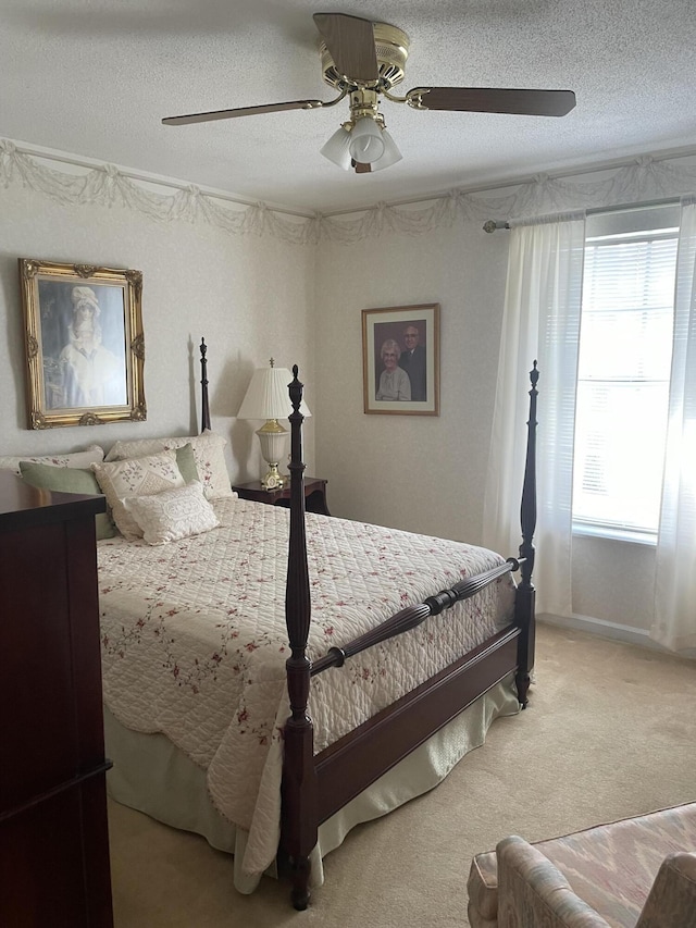 bedroom with a textured ceiling, light colored carpet, and ceiling fan