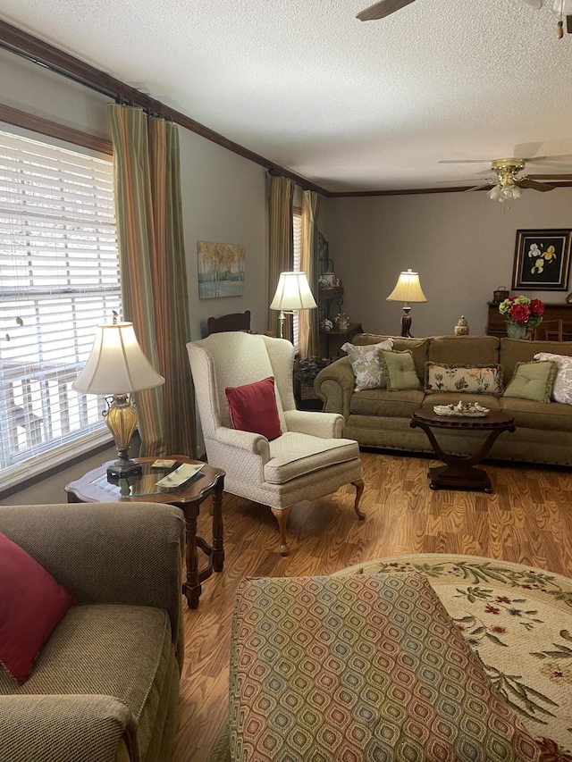 living area featuring a textured ceiling, a ceiling fan, wood finished floors, and ornamental molding