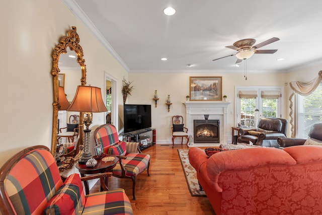 living room featuring light hardwood / wood-style floors, ceiling fan, and crown molding