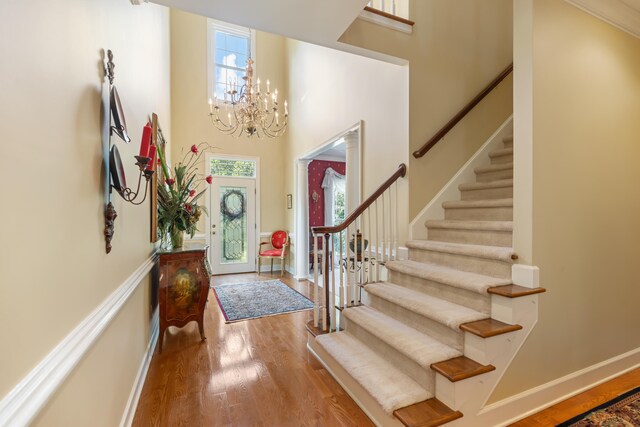 foyer featuring an inviting chandelier, a towering ceiling, and hardwood / wood-style flooring