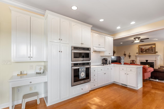 kitchen with ceiling fan, light hardwood / wood-style flooring, double oven, kitchen peninsula, and white cabinets