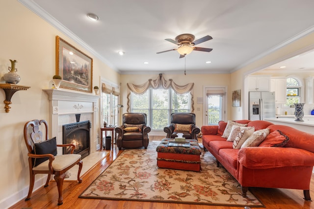 living room with a fireplace, light wood-type flooring, ceiling fan, and ornamental molding