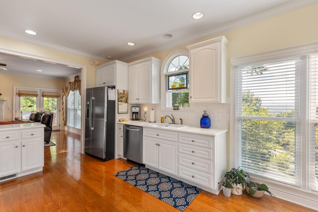 kitchen featuring crown molding, sink, light hardwood / wood-style floors, white cabinetry, and stainless steel appliances