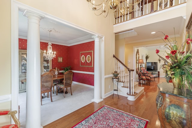 dining space featuring ornate columns, ornamental molding, a notable chandelier, and hardwood / wood-style flooring