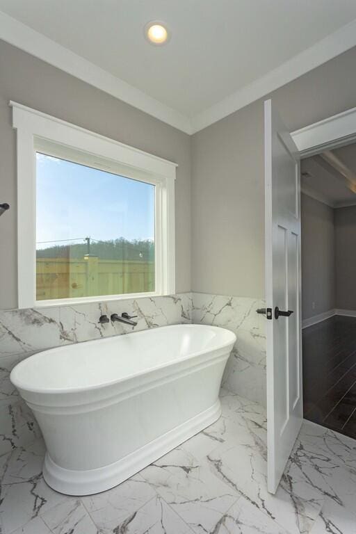 bathroom featuring a washtub, tile walls, and crown molding