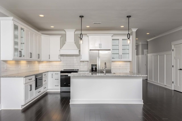 kitchen featuring white cabinets, appliances with stainless steel finishes, pendant lighting, and custom range hood