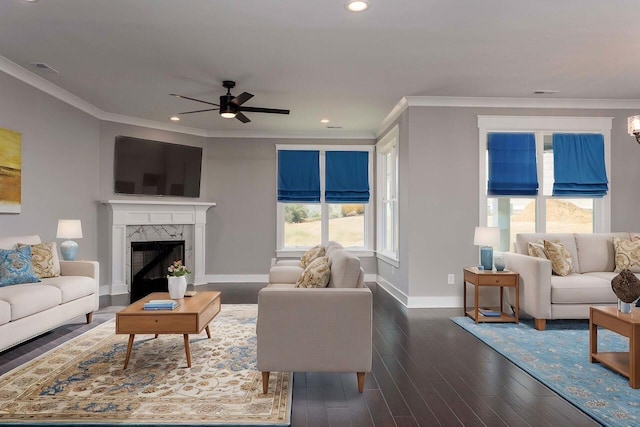 living room with ceiling fan, a high end fireplace, dark hardwood / wood-style flooring, and crown molding