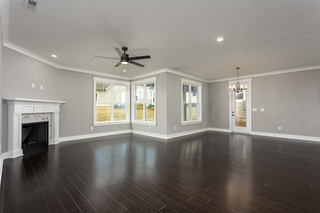 unfurnished living room with dark wood-type flooring, a high end fireplace, ornamental molding, and ceiling fan with notable chandelier