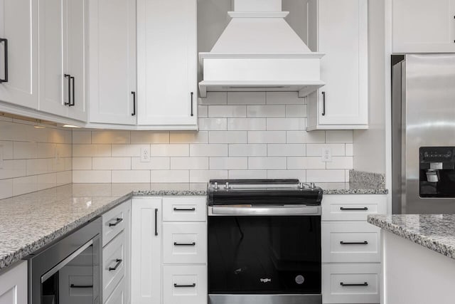 kitchen with backsplash, white cabinets, custom range hood, and stainless steel appliances