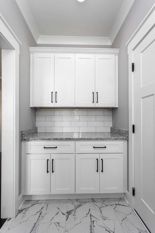 bar featuring white cabinets, backsplash, and ornamental molding