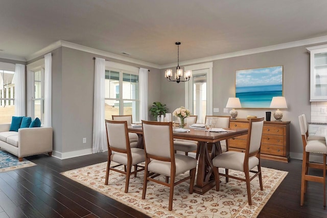 dining space featuring dark hardwood / wood-style flooring, ornamental molding, and a chandelier