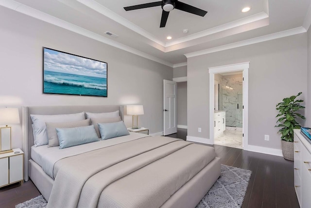 bedroom featuring ceiling fan, dark hardwood / wood-style flooring, a tray ceiling, and connected bathroom