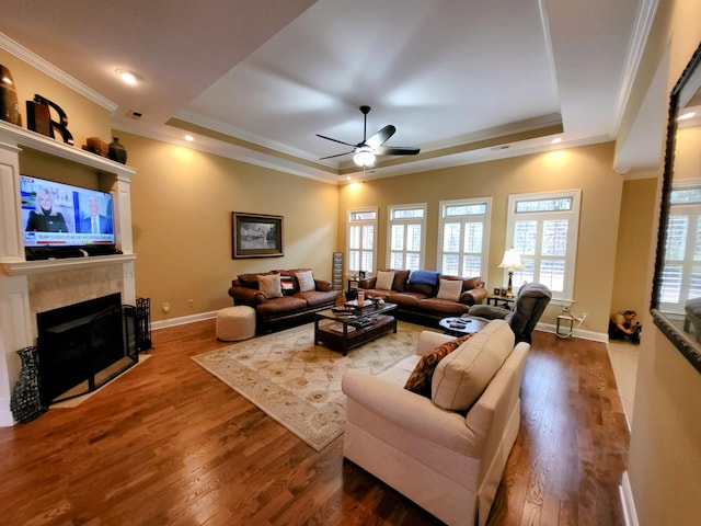 living room with a tray ceiling, wood-type flooring, and ornamental molding