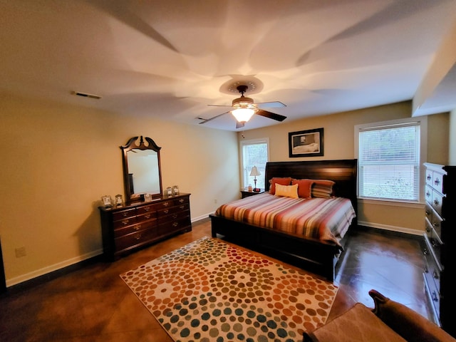 bedroom with multiple windows, dark tile patterned flooring, and ceiling fan