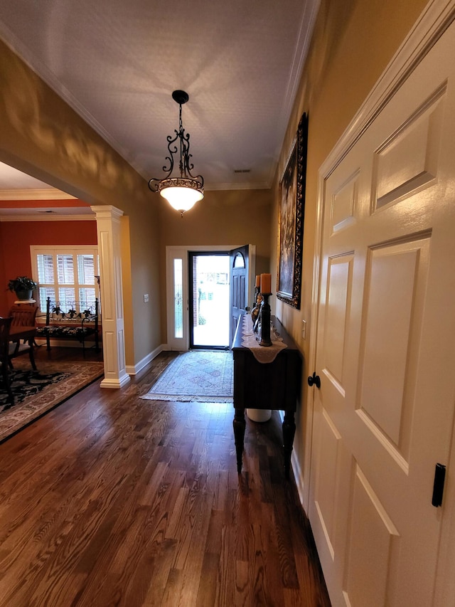 foyer entrance with decorative columns, crown molding, and dark wood-type flooring