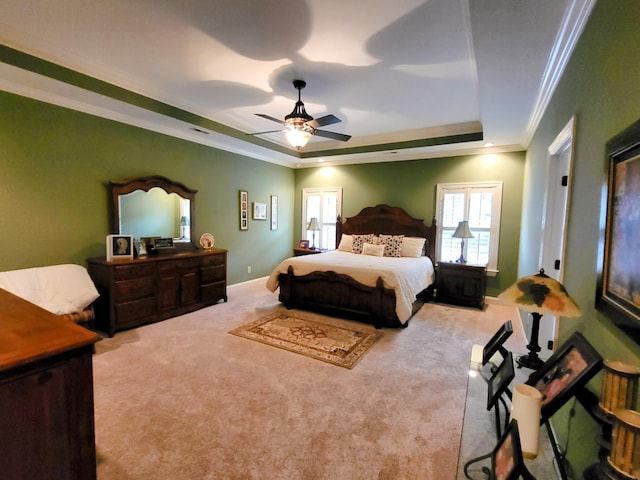 carpeted bedroom with crown molding, ceiling fan, and a tray ceiling