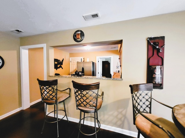 kitchen with a breakfast bar, stainless steel fridge, and kitchen peninsula