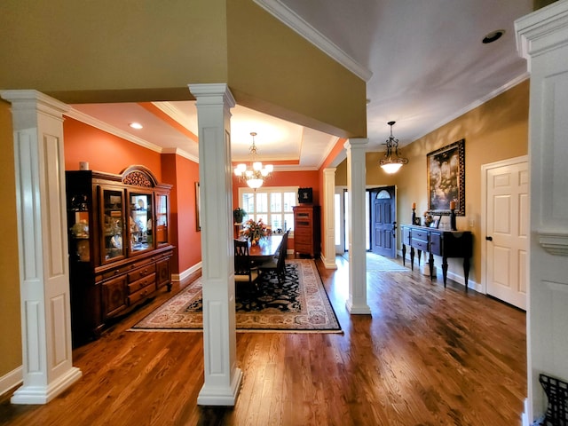 dining area with an inviting chandelier, crown molding, dark wood-type flooring, and decorative columns