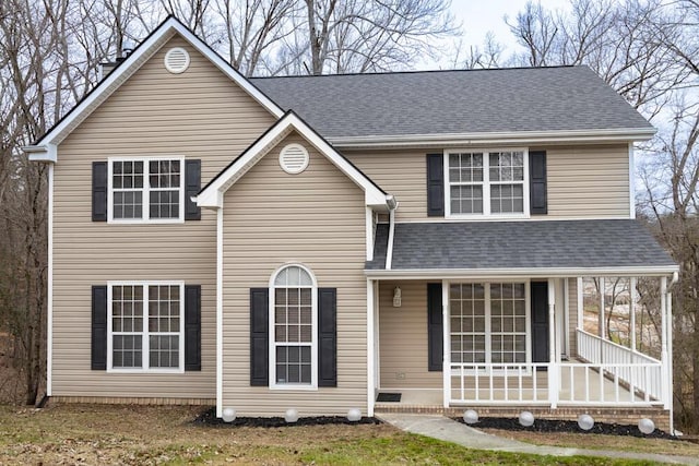 traditional-style house featuring covered porch and roof with shingles