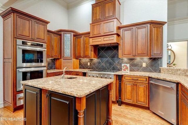 kitchen with crown molding, a kitchen island with sink, stainless steel appliances, light stone counters, and decorative backsplash