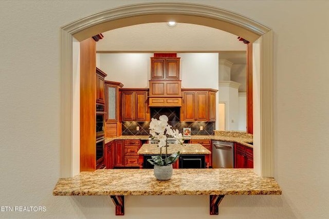 kitchen with tasteful backsplash, light stone counters, stainless steel appliances, and a kitchen bar