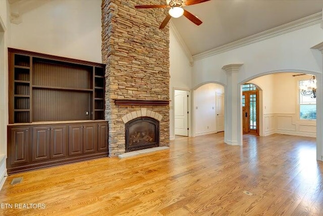 unfurnished living room featuring high vaulted ceiling, a fireplace, ceiling fan, crown molding, and light wood-type flooring