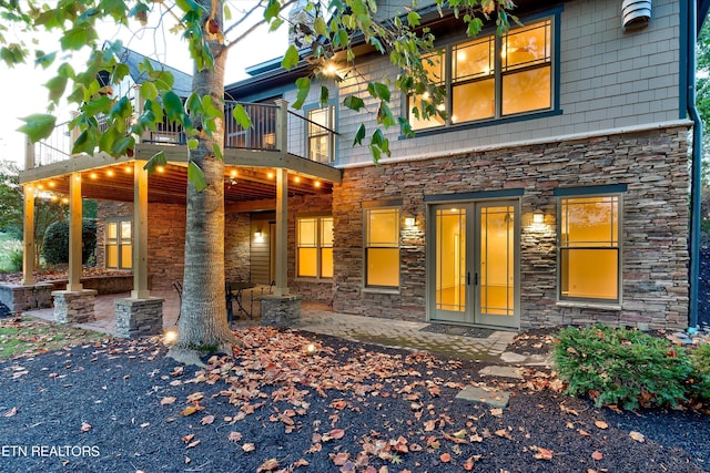 view of front facade with french doors, a balcony, and a patio area