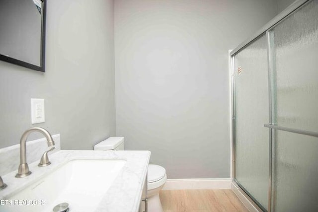 bathroom featuring wood-type flooring, toilet, an enclosed shower, and sink