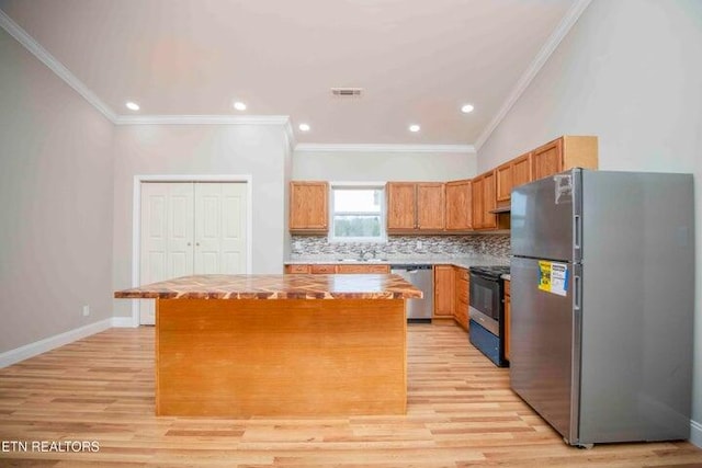 kitchen featuring ornamental molding, a center island, stainless steel appliances, and light hardwood / wood-style floors