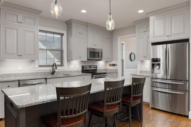 kitchen featuring a center island, sink, hanging light fixtures, stainless steel appliances, and a breakfast bar area