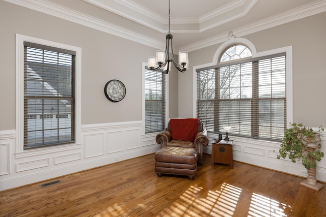 sitting room featuring a tray ceiling, hardwood / wood-style floors, a healthy amount of sunlight, and ornamental molding