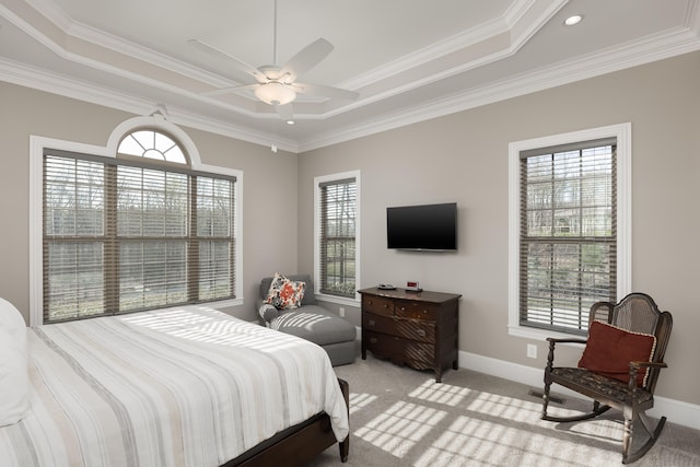 carpeted bedroom with a tray ceiling, ceiling fan, and crown molding