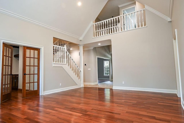 empty room with dark wood-style floors, crown molding, decorative columns, stairway, and high vaulted ceiling