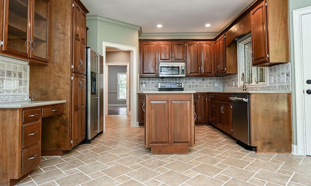 kitchen with decorative backsplash, a kitchen island, crown molding, appliances with stainless steel finishes, and sink