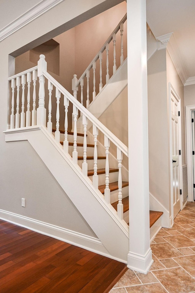 staircase with crown molding, baseboards, and wood finished floors