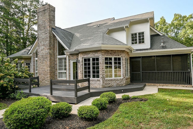 back of house featuring a yard, a sunroom, and a wooden deck