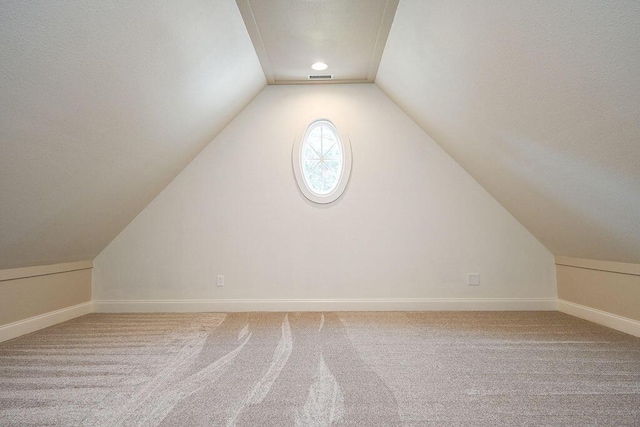 additional living space with baseboards, vaulted ceiling, and carpet flooring