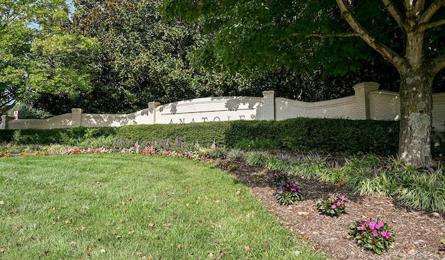 community / neighborhood sign with a lawn and fence