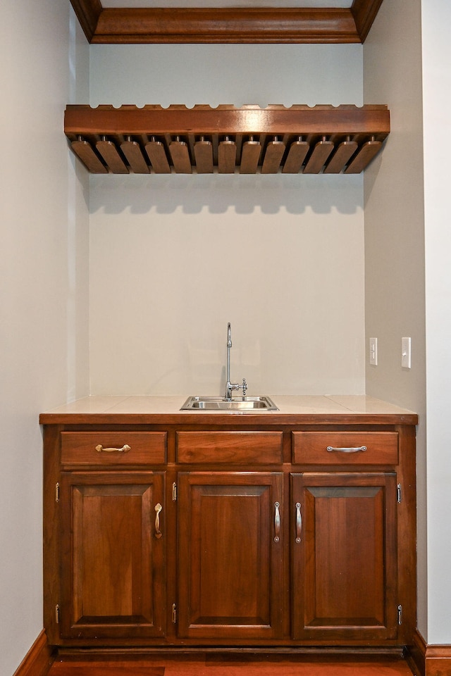 bar with wet bar, ornamental molding, and a sink