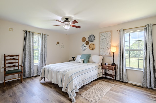 bedroom featuring wood-type flooring, multiple windows, and ceiling fan