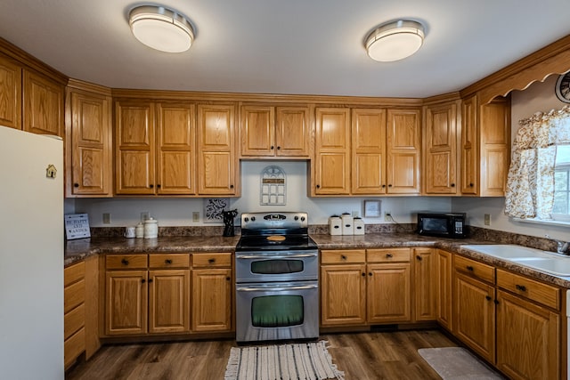 kitchen with white refrigerator, dark wood-type flooring, stainless steel range with electric cooktop, and sink