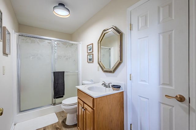 bathroom with toilet, a shower with door, vanity, and hardwood / wood-style flooring