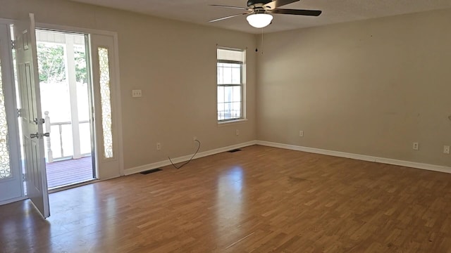 empty room featuring ceiling fan, dark wood-type flooring, and a healthy amount of sunlight