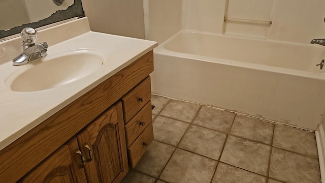 bathroom with tile patterned floors, a tub, and vanity