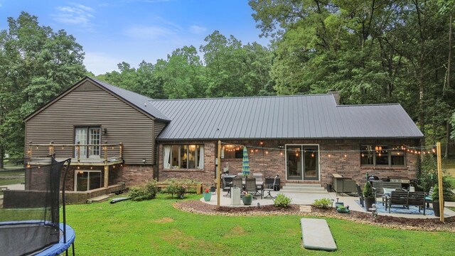364 Hidden Oaks Trl, Cleveland, TN 37312 - rear view of house featuring a patio area, a trampoline, brick siding, a lawn, and a metal roof