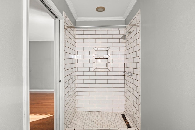 bathroom with a tile shower and ornamental molding