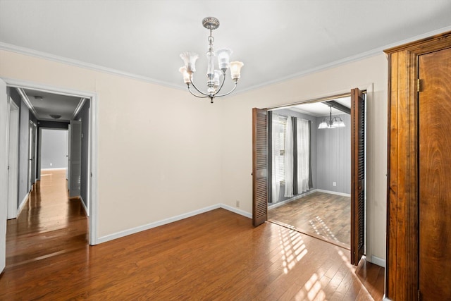 unfurnished room featuring dark hardwood / wood-style flooring, ornamental molding, and an inviting chandelier